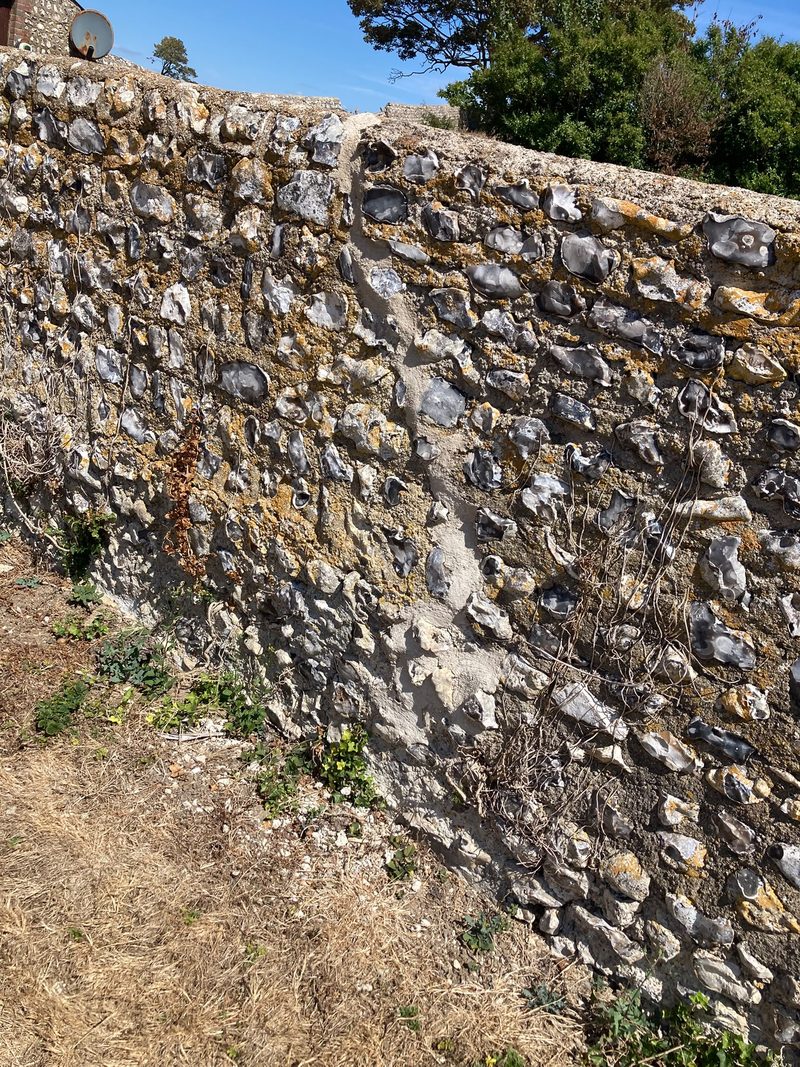 Close view of a knapped flint wall, the dark split faces of the flints set in pale lime mortar