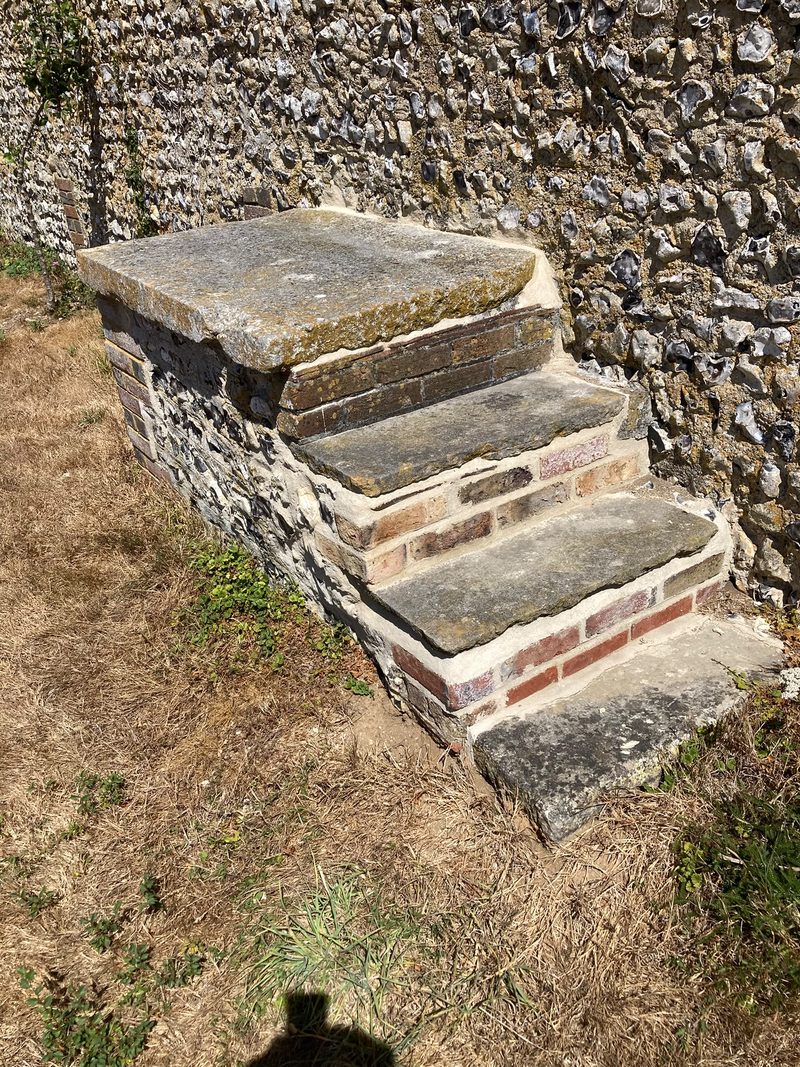 Stone steps with brick risers against a flint wall