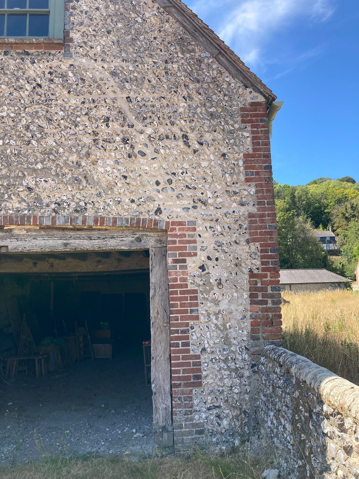 A coursed flint elevation with a brick-arched opening and brick quoins