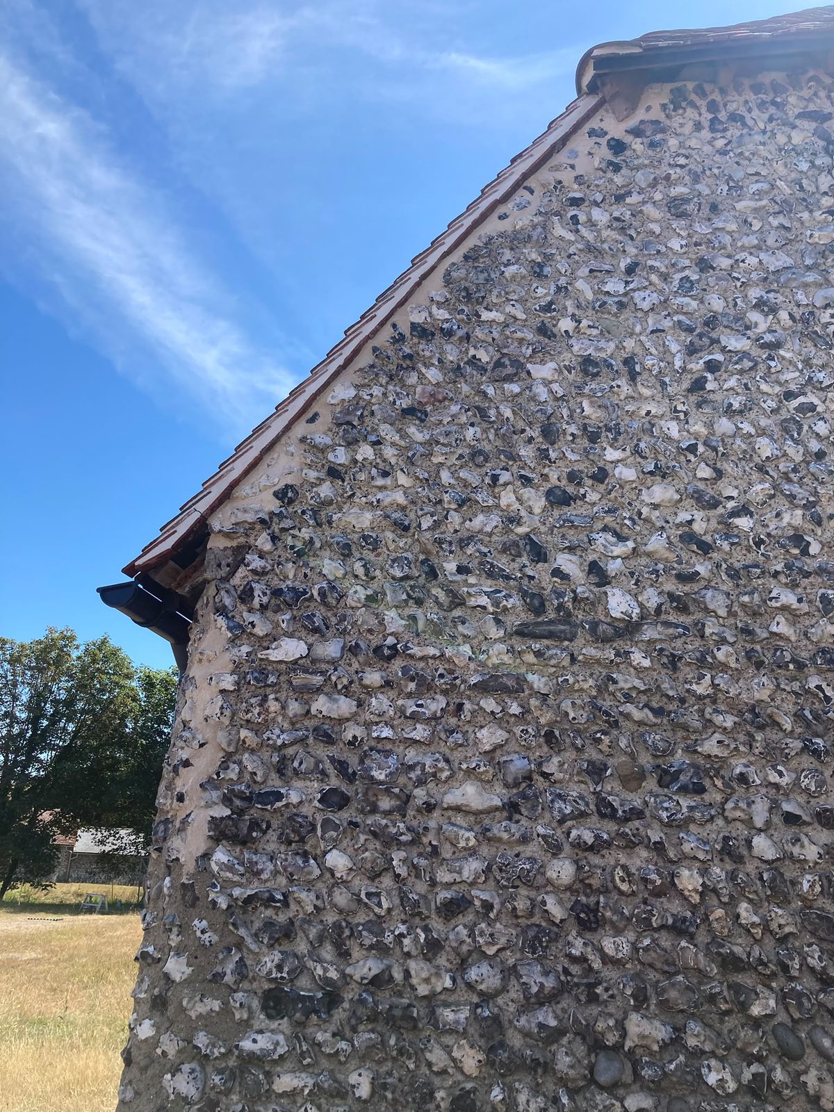 A knapped flint gable end rising against a blue sky